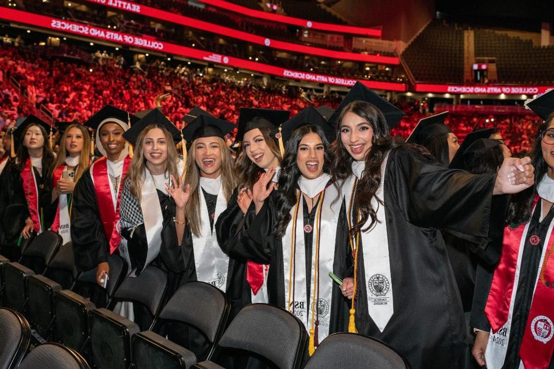 Undergrad students smiling and waving at camera during commencement